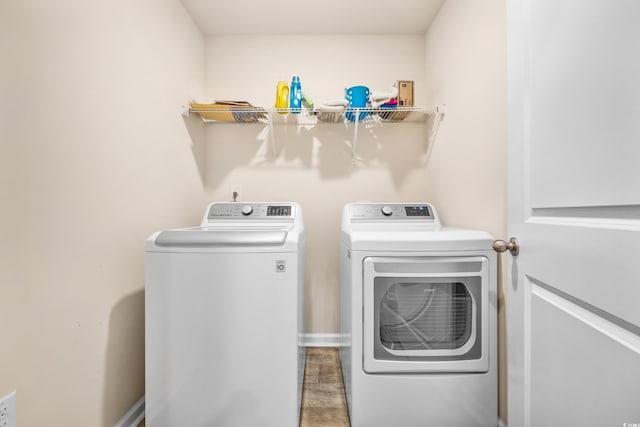 clothes washing area featuring wood-type flooring and separate washer and dryer