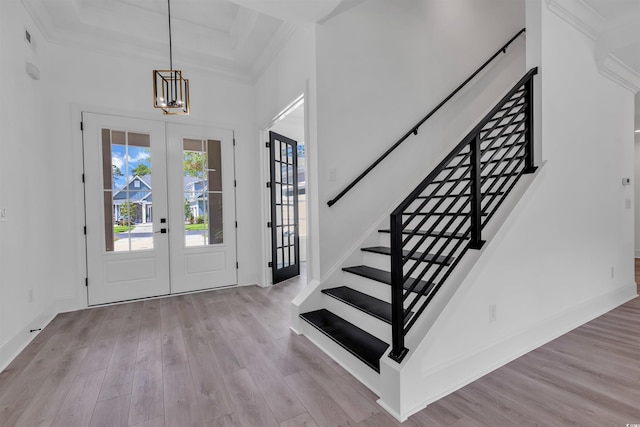 entrance foyer featuring ornamental molding, light hardwood / wood-style flooring, french doors, and a notable chandelier