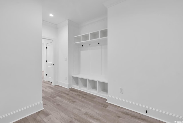 mudroom featuring built in shelves, ornamental molding, and light hardwood / wood-style floors