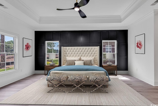 bedroom featuring ceiling fan, crown molding, light hardwood / wood-style flooring, and a raised ceiling