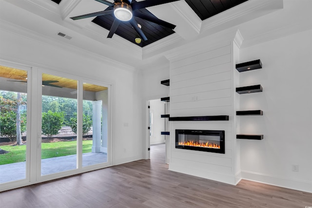 unfurnished living room with hardwood / wood-style flooring, coffered ceiling, ceiling fan, a large fireplace, and ornamental molding