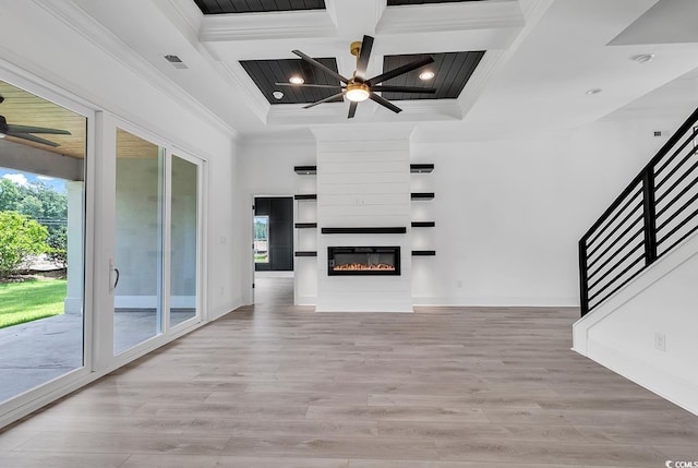 unfurnished living room featuring light hardwood / wood-style floors, coffered ceiling, a fireplace, crown molding, and beamed ceiling