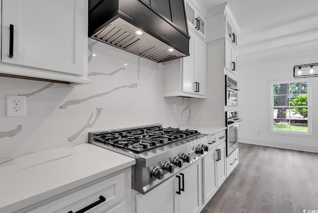 kitchen featuring white cabinetry, wall chimney range hood, and stainless steel appliances