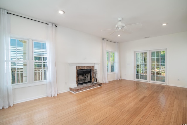 unfurnished living room with light hardwood / wood-style floors, a brick fireplace, and ceiling fan