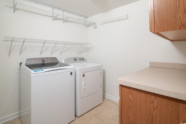 clothes washing area featuring cabinets and separate washer and dryer