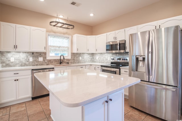 kitchen featuring a kitchen island, decorative backsplash, stainless steel appliances, sink, and white cabinets