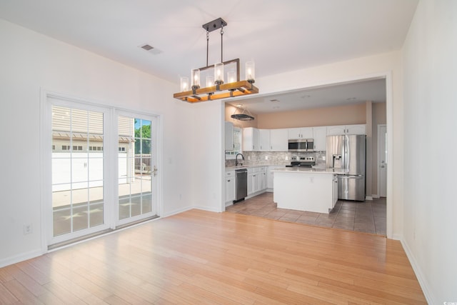 kitchen featuring stainless steel appliances, light wood-type flooring, a kitchen island, and hanging light fixtures