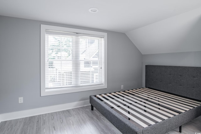 bedroom with vaulted ceiling and light hardwood / wood-style flooring