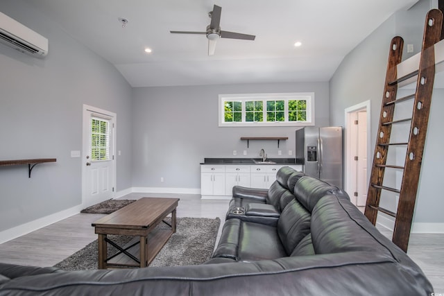 living room featuring a wall unit AC, lofted ceiling, light hardwood / wood-style flooring, and a wealth of natural light