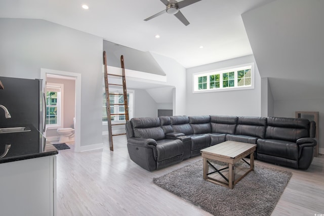 living room featuring lofted ceiling, sink, light wood-type flooring, and ceiling fan