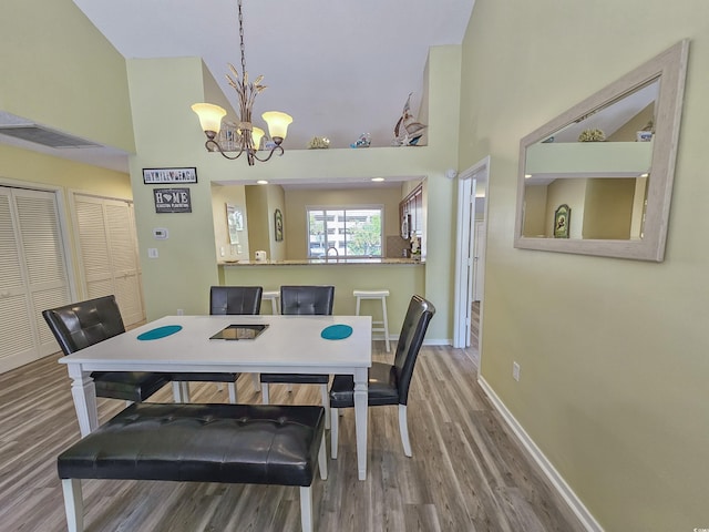 dining room featuring a high ceiling, hardwood / wood-style floors, and a chandelier