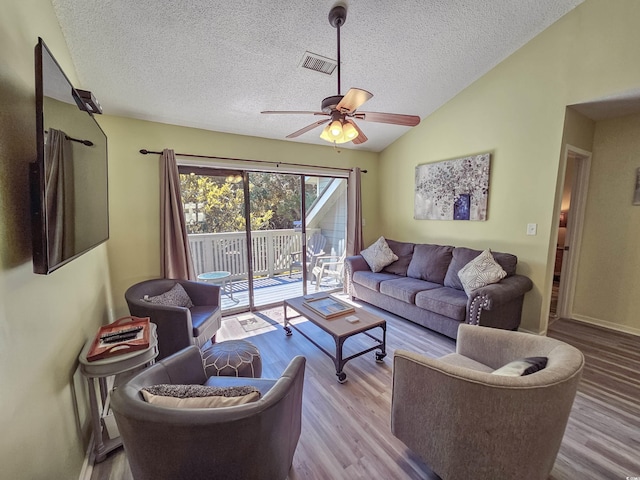 living room with a textured ceiling, light hardwood / wood-style floors, lofted ceiling, and ceiling fan