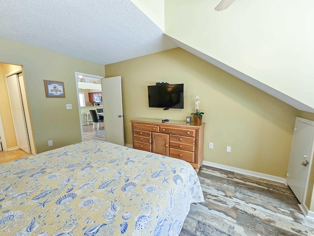 bedroom featuring vaulted ceiling, ceiling fan, hardwood / wood-style flooring, and a textured ceiling