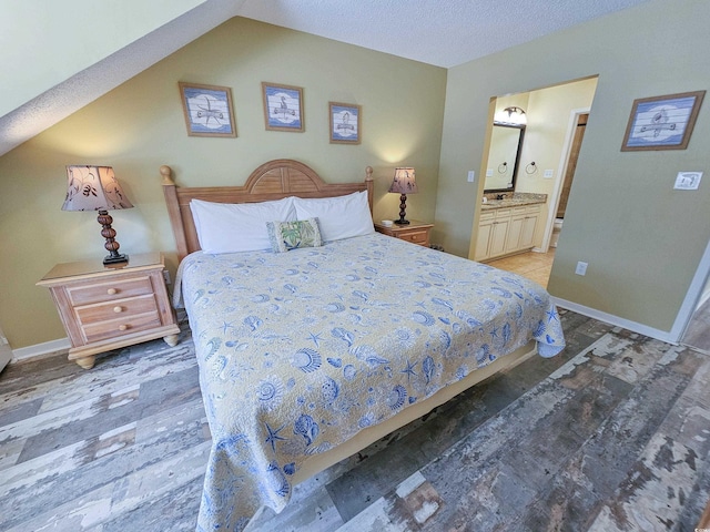 bedroom featuring vaulted ceiling, a textured ceiling, and ensuite bathroom