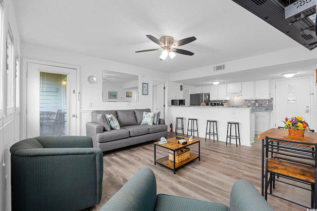 living area with ceiling fan, light wood finished floors, and visible vents