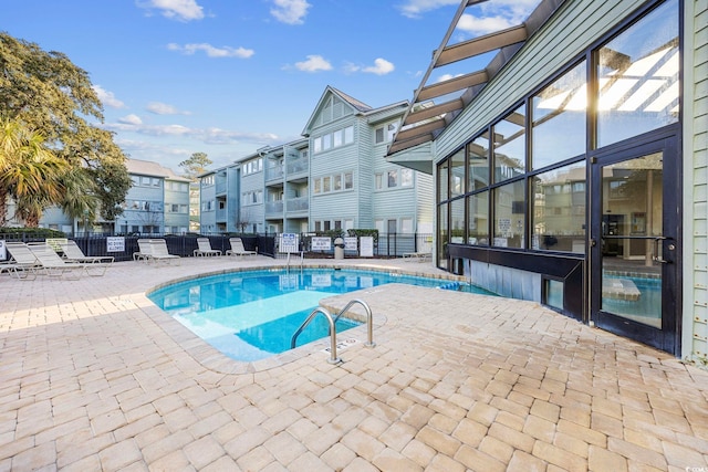 community pool with a patio area, a residential view, and fence