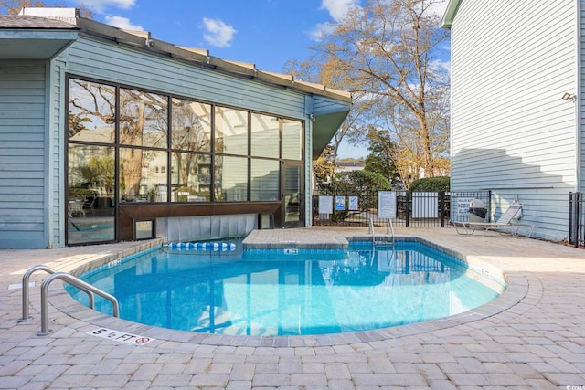 community pool with a patio area and fence