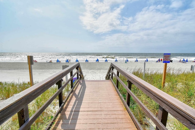 view of property's community with a water view and a beach view