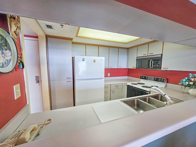 kitchen with visible vents, black microwave, light countertops, electric stove, and freestanding refrigerator