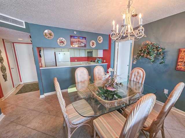 tiled dining room featuring visible vents, baseboards, a textured ceiling, and a notable chandelier