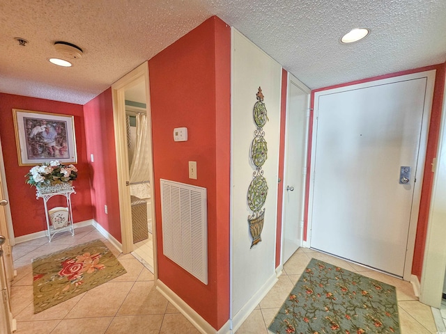 hallway with a textured ceiling and light tile flooring