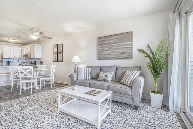 living room featuring a textured ceiling, light hardwood / wood-style floors, ceiling fan, and sink