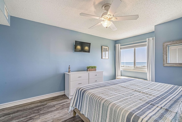 bedroom with ceiling fan, a textured ceiling, and hardwood / wood-style flooring