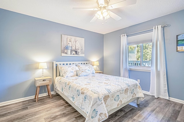 bedroom with ceiling fan, wood-type flooring, and a textured ceiling