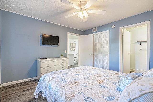 bedroom with ceiling fan, dark hardwood / wood-style flooring, a textured ceiling, and a closet