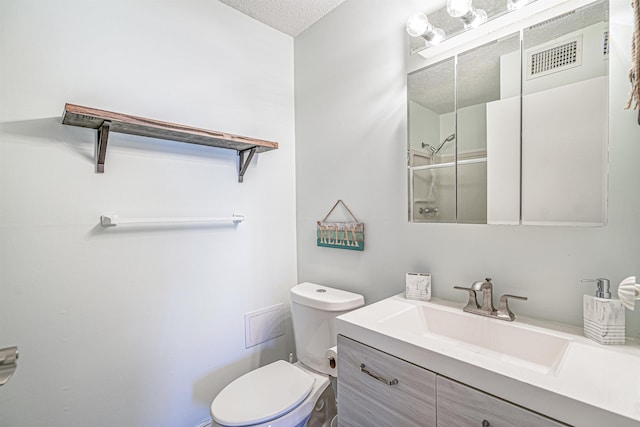 bathroom with vanity, toilet, a shower with door, and a textured ceiling