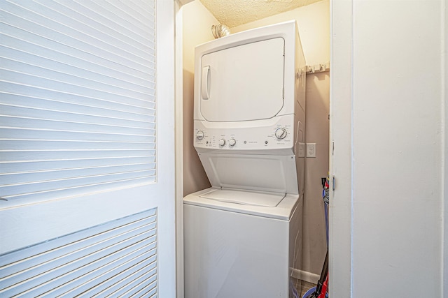 laundry area with stacked washer and dryer and a textured ceiling