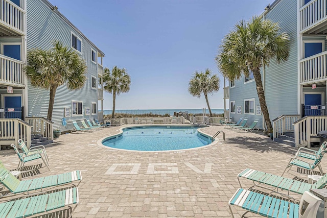 view of pool featuring a water view and a patio