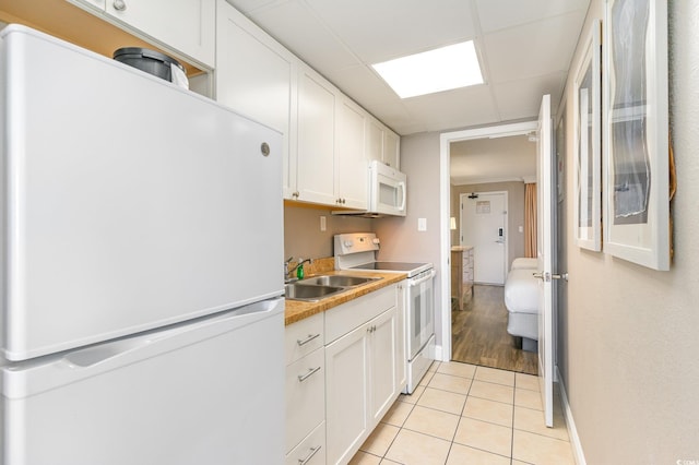 kitchen with white cabinets, white appliances, sink, and light tile patterned floors