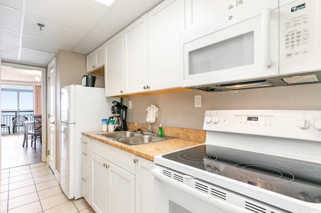 kitchen featuring white cabinetry, sink, light tile patterned floors, and white appliances