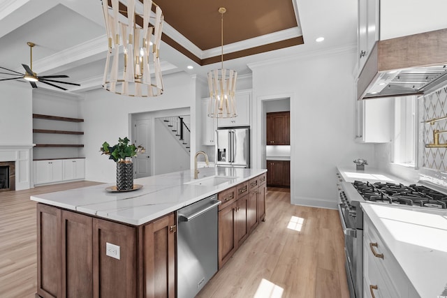 kitchen with pendant lighting, white cabinetry, high end appliances, a kitchen island with sink, and light stone counters