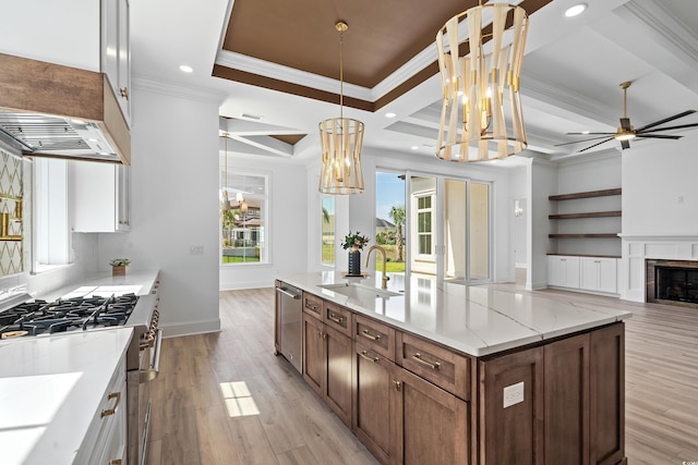 kitchen featuring appliances with stainless steel finishes, decorative light fixtures, ornamental molding, light stone counters, and sink