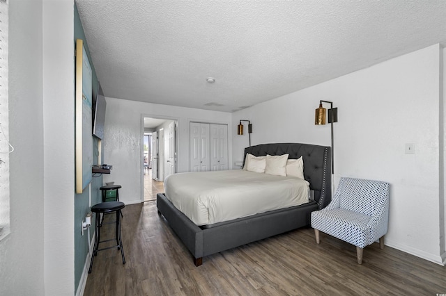 bedroom with a textured ceiling, dark hardwood / wood-style floors, and a closet