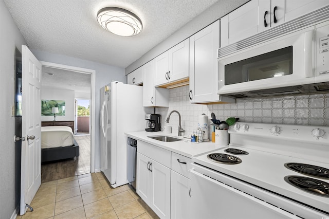 kitchen featuring sink, light tile patterned floors, white appliances, decorative backsplash, and white cabinets