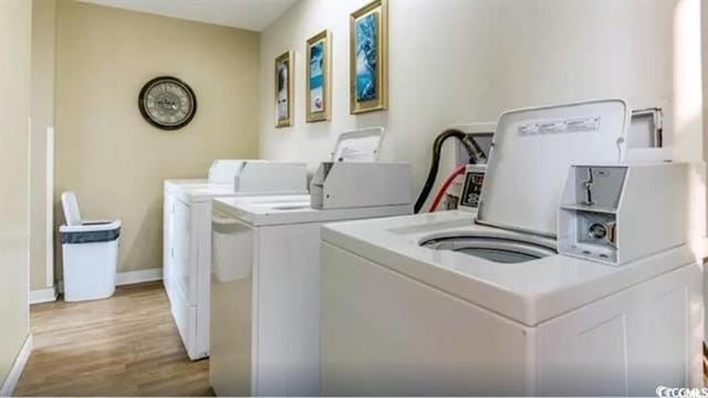 laundry area featuring separate washer and dryer and light hardwood / wood-style flooring