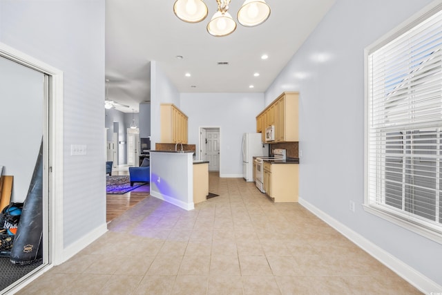 kitchen featuring a kitchen breakfast bar, light tile patterned floors, a healthy amount of sunlight, and white appliances