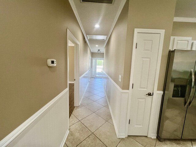 hallway featuring light tile patterned flooring and crown molding