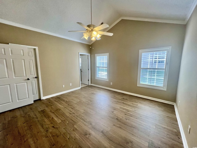 unfurnished bedroom with wood-type flooring, vaulted ceiling, ornamental molding, and a textured ceiling