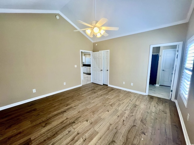 unfurnished bedroom featuring crown molding, vaulted ceiling, ceiling fan, and light wood-type flooring