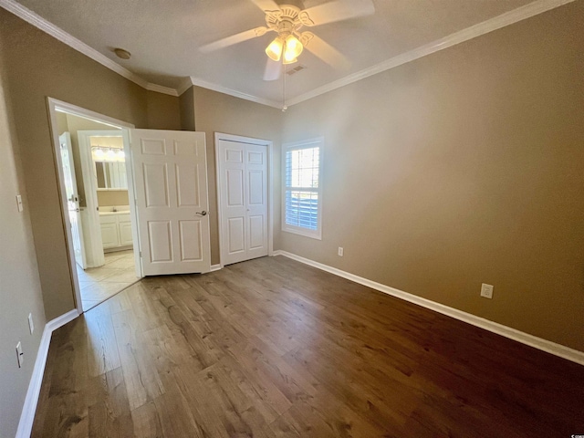 unfurnished bedroom with wood-type flooring, ornamental molding, a closet, and ceiling fan