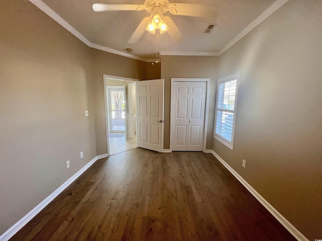 unfurnished bedroom with ceiling fan, ornamental molding, dark hardwood / wood-style flooring, and a closet