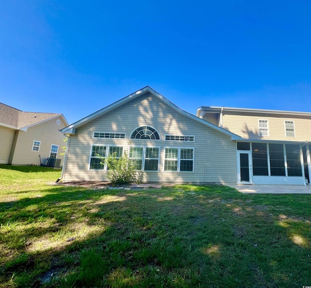 rear view of house with central AC, a yard, and a sunroom