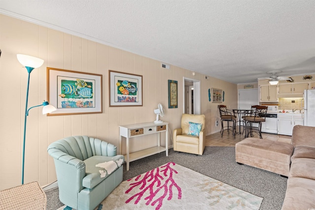 carpeted living room with ceiling fan and a textured ceiling