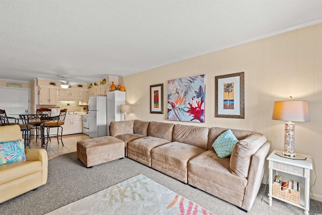 carpeted living room with ceiling fan, a textured ceiling, and ornamental molding