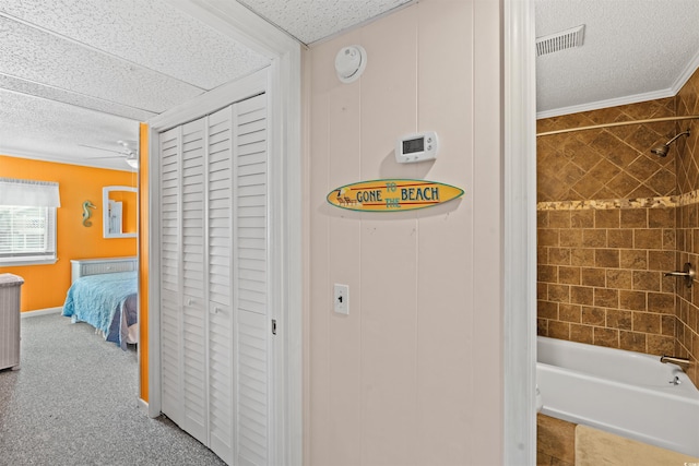 interior space with a textured ceiling, tiled shower / bath, and crown molding