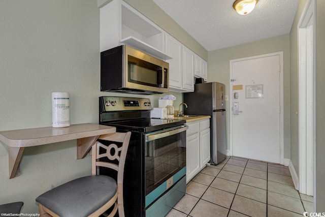 kitchen featuring white cabinets, sink, light tile patterned floors, and stainless steel appliances